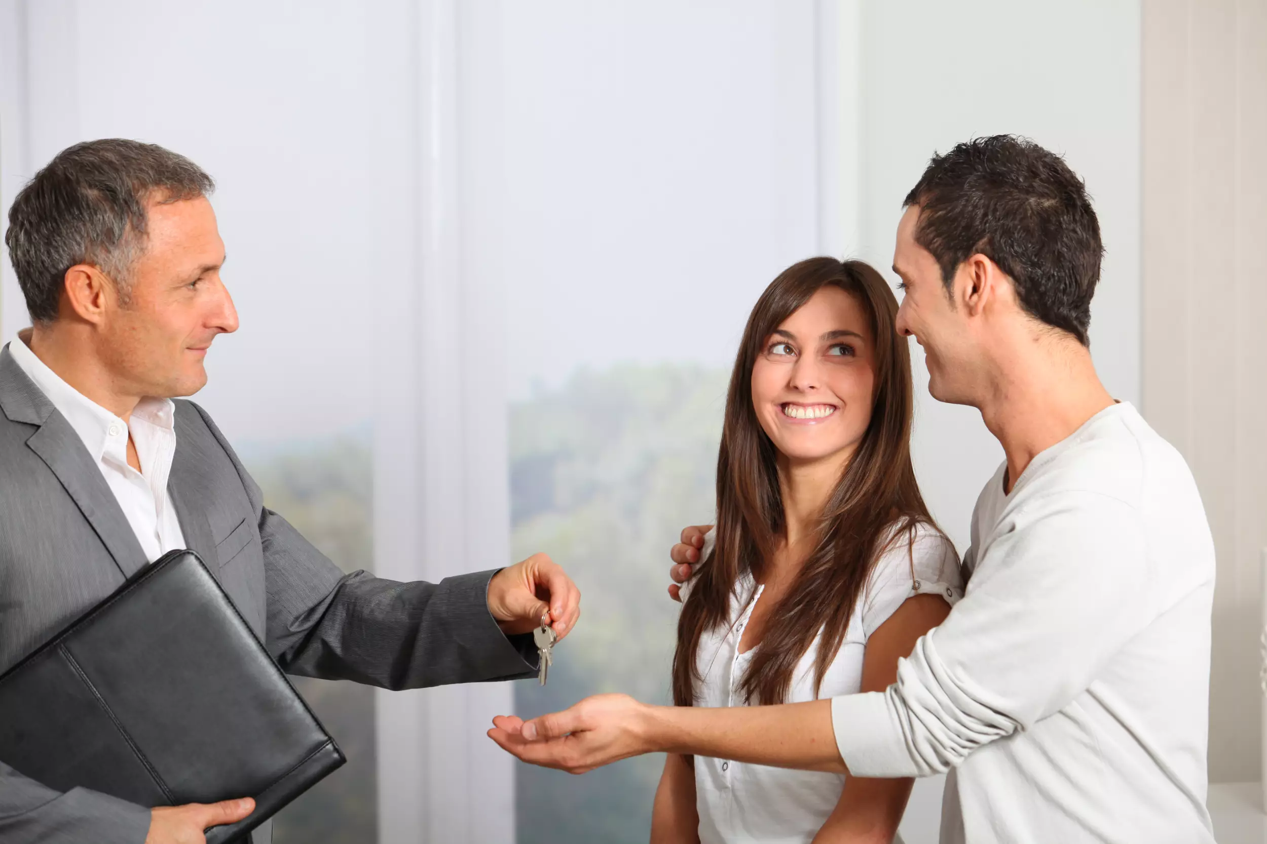 A young couple being handed keys to a new home