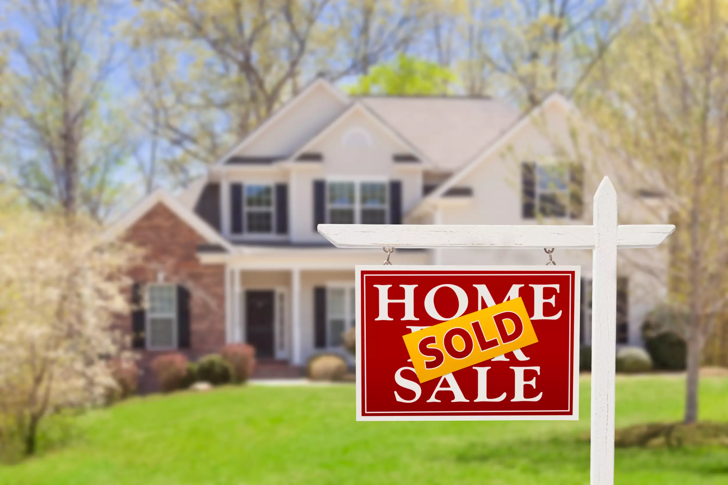 A 2-story home with a Sold sign in the front yard